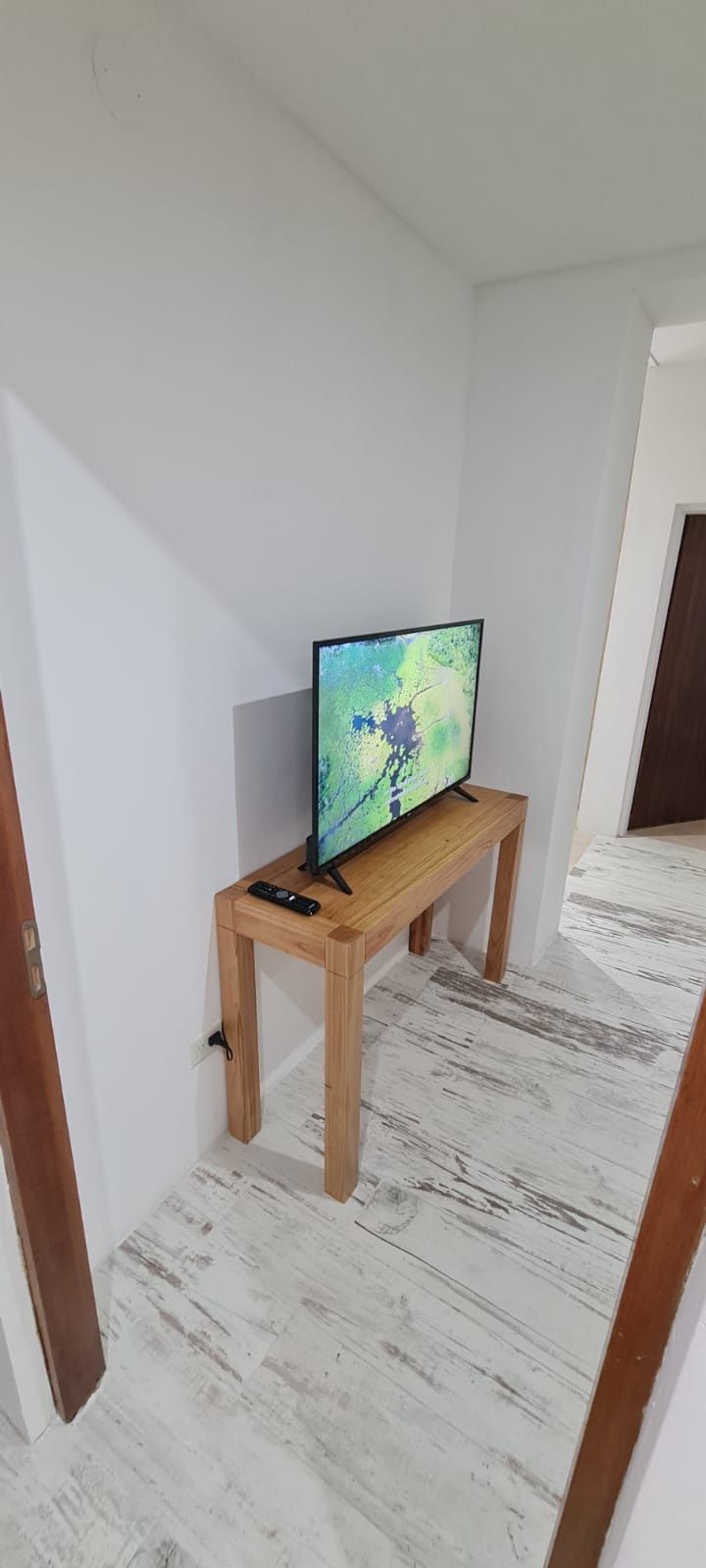 Een kamer met een houten tv-meubel waarop een flatscreen televisie en een afstandsbediening staan.