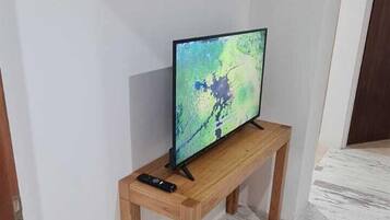 Een kamer met een houten tv-meubel waarop een flatscreen televisie en een afstandsbediening staan.