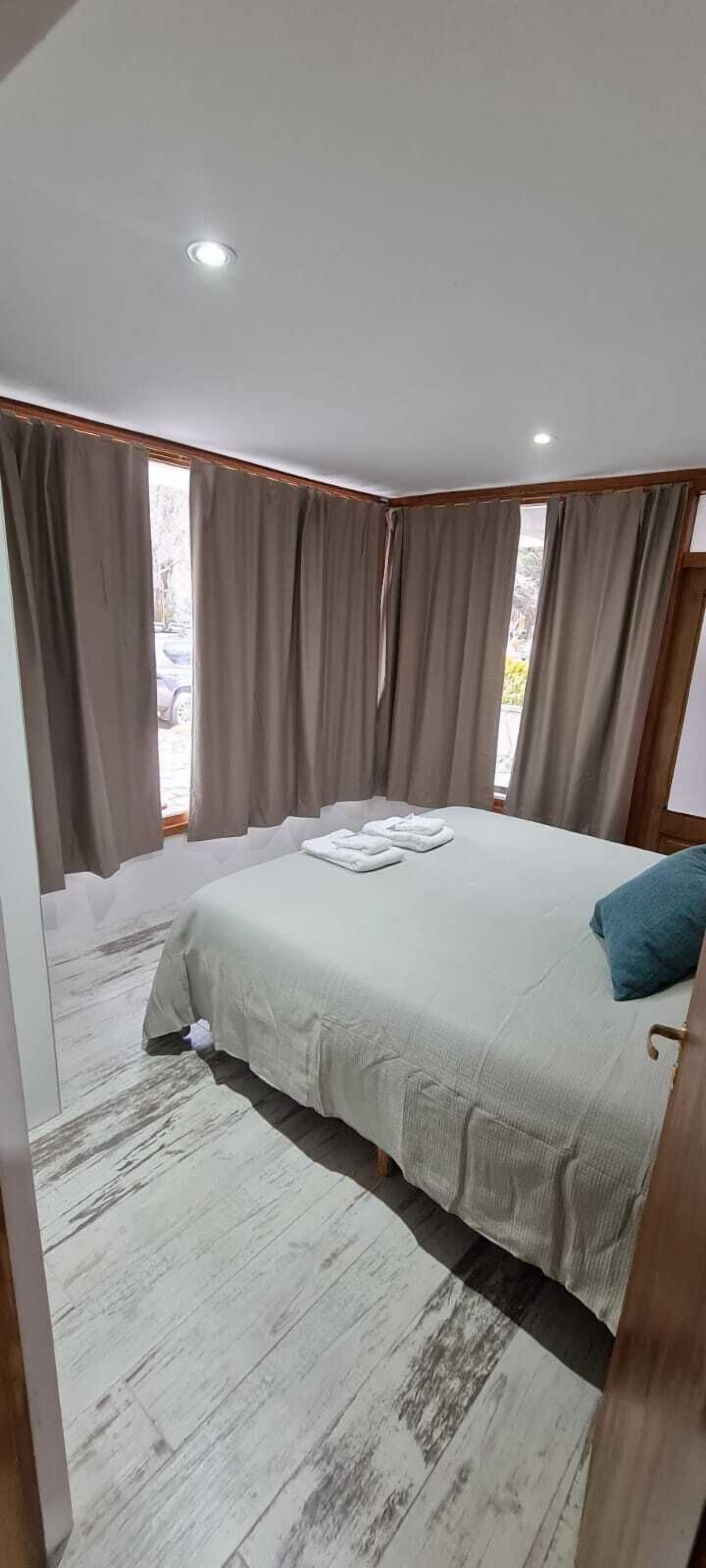 A bedroom with a bed, curtains, and a window.