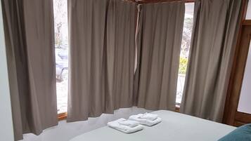 A bedroom with a bed, curtains, and a window.