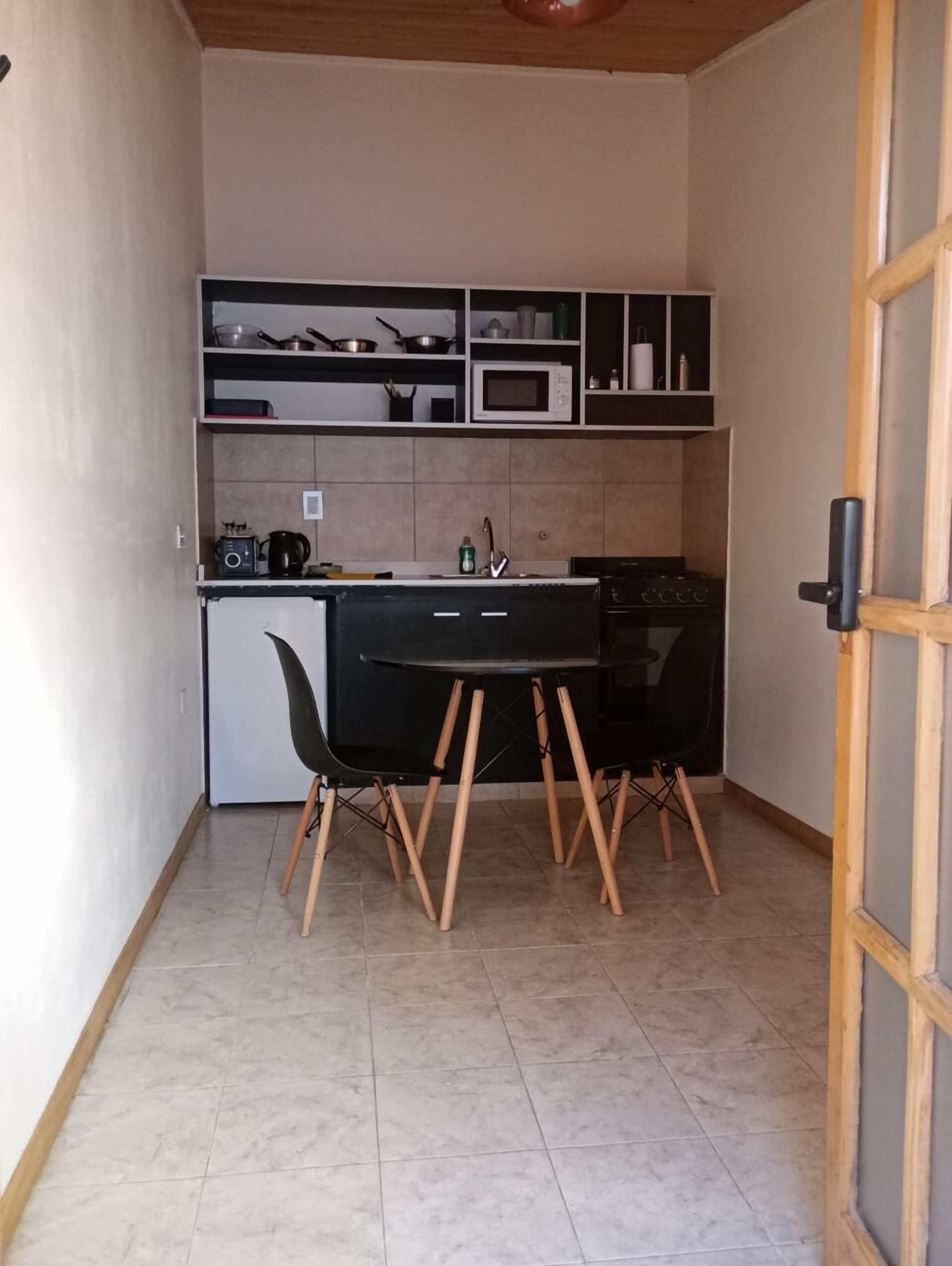 A compact kitchen with a black table and chairs, a microwave, and a small stove.