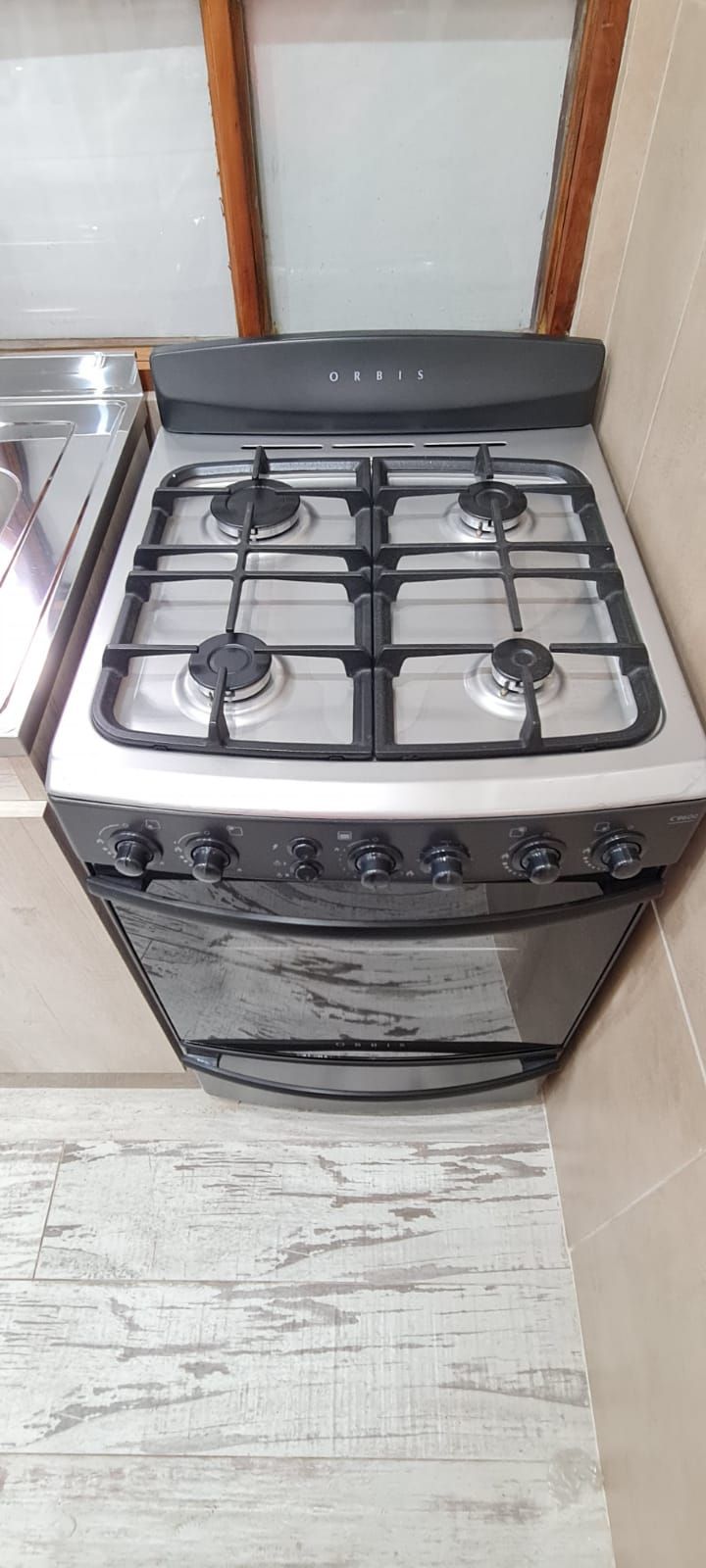 Una cocina con estufa a gas, horno y pileta de acero inoxidable.