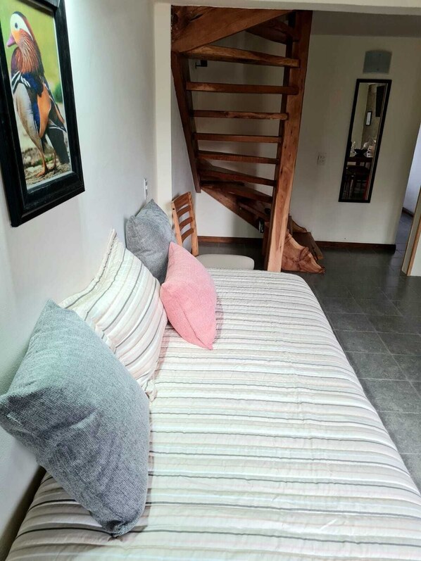 A bedroom with a bed, pillows, a wooden staircase, and a framed picture on the wall. - PUERTO LACAR LODGE SMARG (San Martín de los Andes)