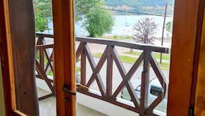 A wooden door leading to a balcony with a view of a lake and mountains. - PUERTO LACAR LODGE SMARG (San Martín de los Andes)