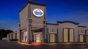A suburban hotel with a prominent sign, a covered entrance, and a parking lot. - Suburban Studios Chester I-95, VA (Chester)