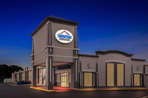 A suburban hotel with a prominent sign, a covered entrance, and a parking lot. - Suburban Studios Chester I-95, VA (Chester)