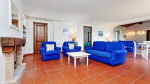 Ein geräumiges Wohnzimmer mit blauen Sofas, einem weißen Couchtisch und einem Kamin.