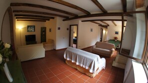 A spacious living area with a tiled floor, a sofa, a chair, and a covered table.