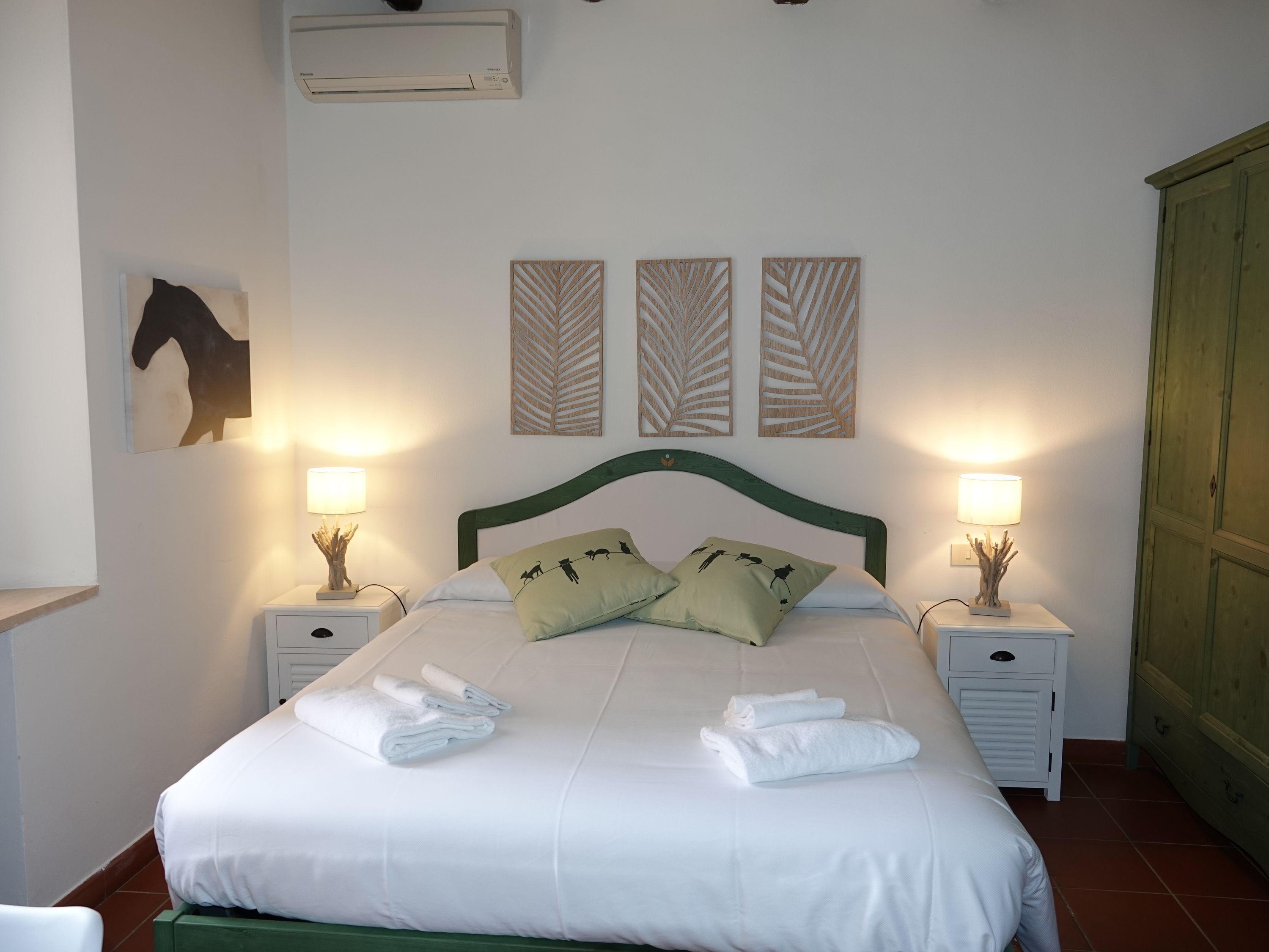 A neatly made bed with white linens and two pillows, flanked by bedside tables with lamps and decorative items.