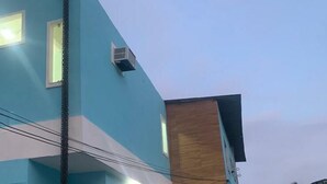 Un edificio de dos pisos con fachada azul y revestimiento de madera. Hay un automóvil estacionado en la parte delantera.