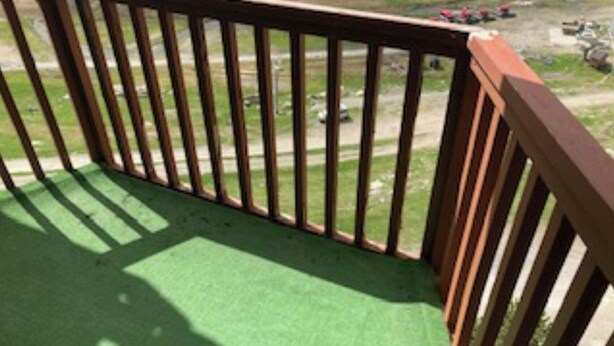 A wooden deck with a green surface, likely a balcony or patio area. - 5-PERSON APARTMENT LA MONGIE AT THE FOOT OF THE SLOPES (Bagnères-de-Bigorre)