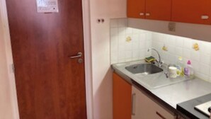 A kitchen with a wooden door, white tiled backsplash, and orange cabinets. - 5-PERSON APARTMENT LA MONGIE AT THE FOOT OF THE SLOPES (Bagnères-de-Bigorre)