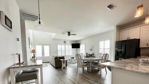 A spacious kitchen with a dining area, wooden flooring, and modern appliances. - Beach Cottage with a View!! (Gulfport)