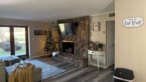 A cozy living room with a stone fireplace, a Christmas tree, and a flat-screen TV mounted above it. - Mountain View Hideaway On A Golf course, Close To Downtown Gatlinburg, Sleeps 6 (Gatlinburg)