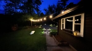Een huis met een verzorgd gazon, een pad dat naar de voordeur leidt en lichtjes langs het pad.