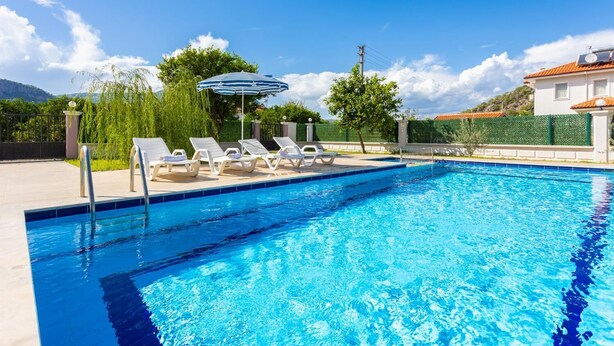 A swimming pool with lounge chairs and an umbrella. - Villa Vista - Four Bedroom Villa, Sleeps 8 (Dalyan)
