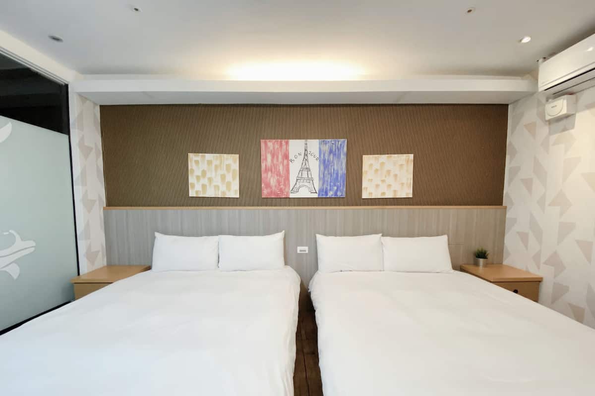 Ein Hotelzimmer mit zwei Betten, einem hölzernen Kopfteil und einer Wand mit drei gerahmten Kunstwerken.
