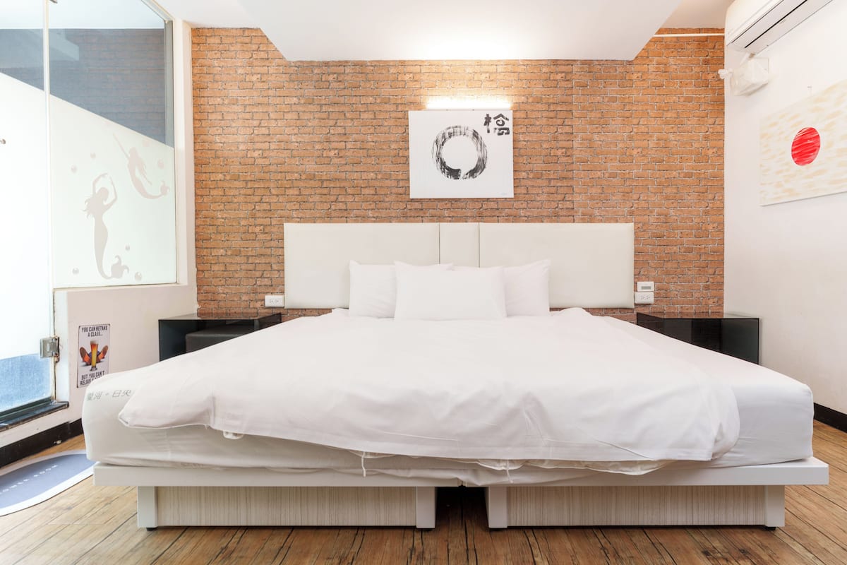 Ein modernes Schlafzimmer mit Backsteinwand, einem weißen Bett und minimalistischem Design.