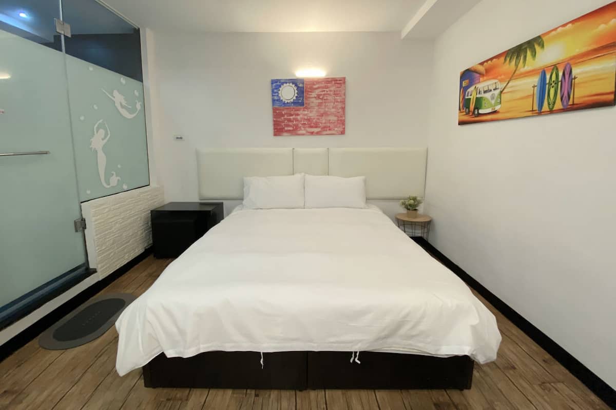 Ein Hotelzimmer mit Bett, Nachttisch, einem kleinen Tisch mit Pflanze, einem Bild an der Wand und einem Kleiderschrank.