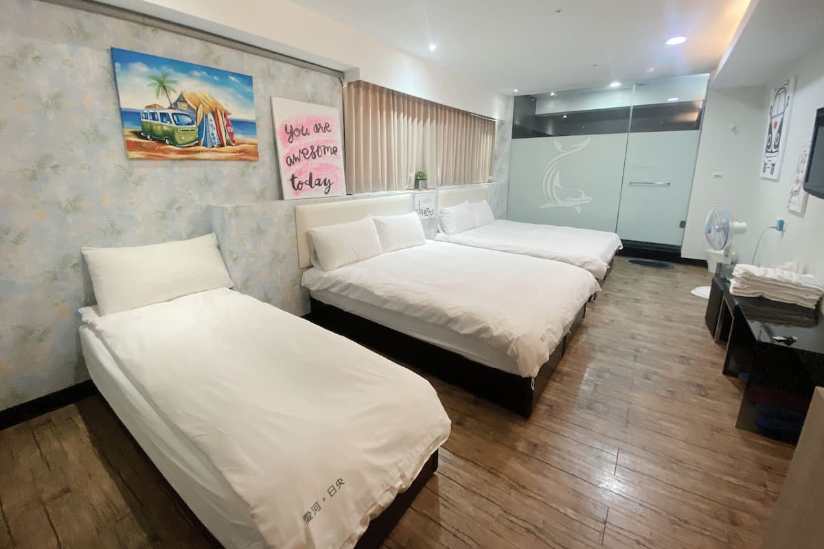 Ein Hotelzimmer mit zwei Einzelbetten, einem großen Spiegel, einem Bild mit Strandmotiv, einem Motivationssprichwort an der Wand und einem Holzboden.