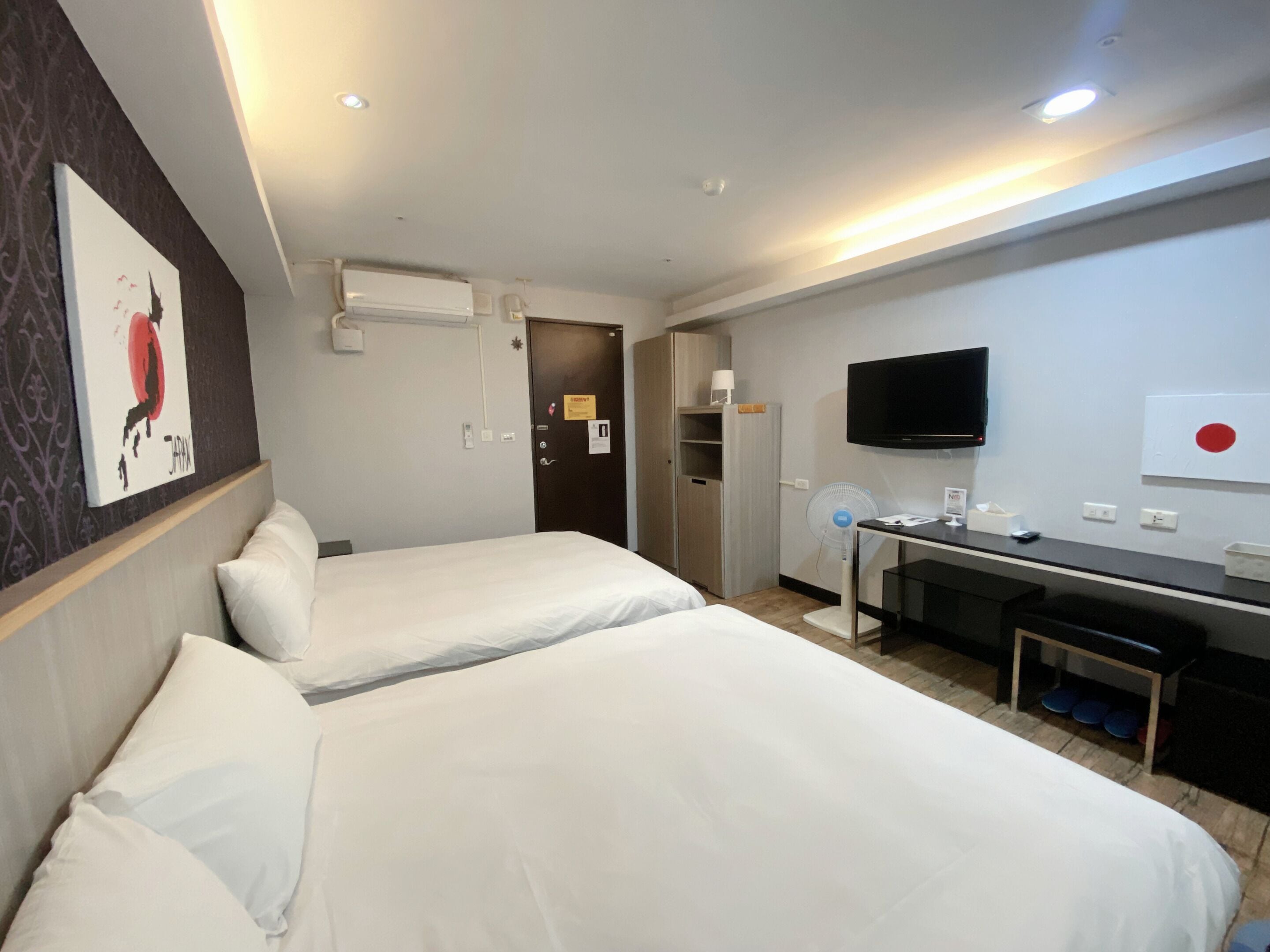 Habitación de hotel con dos camas, un escritorio, televisión y un minibar.