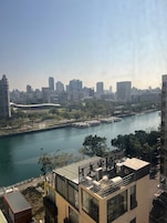 Vista de um rio com um horizonte urbano repleto de edifícios modernos, uma ponte e o rio.