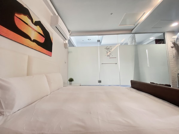A modern bedroom with a large bed, a wall-mounted air conditioner, and a glass partition. - LoveRiverInn (Kaohsiung)