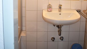 A bathroom with a white sink, a mirror, and a small potted plant. - Posthus Apartment 103, close to the beach and central (Borkum)