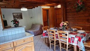 A wooden interior with a dining table set for four, wooden cabinets, and a sofa. - Chalet Genépi - Apartment 1 (Le Grand-Bornand)