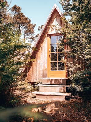 Eine Holzhütte mit Satteldach, einer Holztür und einer kleinen Veranda.