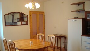 A dining area with a wooden table and chairs, a small kitchen area with a refrigerator, and a mirror on the wall. - Dream view - family apartment with terrace and garden (Lezzeno)