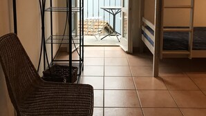 A room with a wicker chair, a metal shelf unit, a white table, and a bunk bed. - Dream view - family apartment with terrace and garden (Lezzeno)