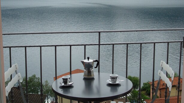 A balcony with a table, two cups, and a coffee pot. - Dream view - family apartment with terrace and garden (Lezzeno)