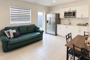 A modern kitchen with white cabinets, a stainless steel refrigerator, and a microwave. - Private & Comfy Efficiency (Miami)