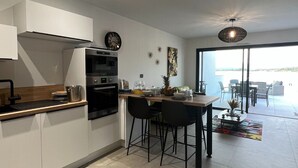 A modern kitchen with a dining area, featuring a large window and a view of the outdoors. - Waterfront terrace apartment in PORTICCIO (Grosseto-Prugna)