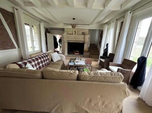Cozy living room with a fireplace, sofa, and armchairs, offering a comfortable seating area.