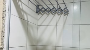 Une douche avec une porte en verre, une barre d’appui en métal et un porte-serviettes.