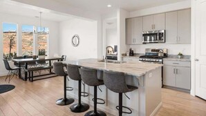 A modern kitchen with a central island, bar stools, and a dining area with a view. - Vaca Casa: Hot Tub, Arcades, Foosball. Pickleball (Washington)