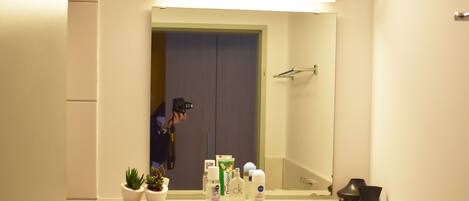 A bathroom with a sink, mirror, and toiletries.