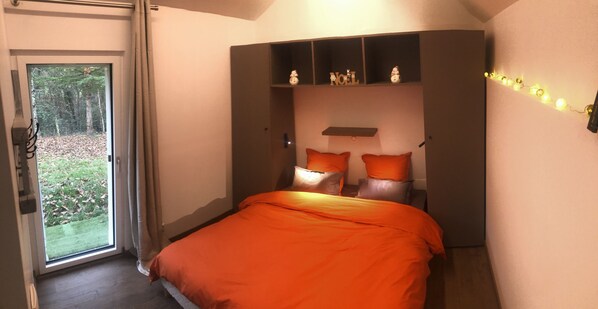 Un dormitorio con cama, ventana y estante con objetos decorativos.
