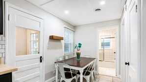 A dining area with a table, chairs, a vase, and a window with blinds. - Stylish, Cute & Homey Livonia Getaway (Livonia)