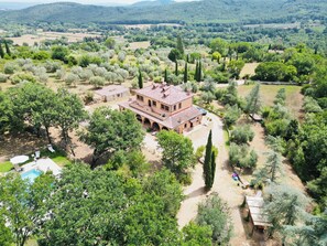A large, two-story building with a courtyard, surrounded by lush greenery and trees. - Villa Cresci with Pool: Tuscan Villa with Pool Near the Sassetta Thermal Baths (Sassetta)