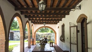 Une terrasse couverte avec un plafond en bois, des colonnes en briques et une table avec des bancs.