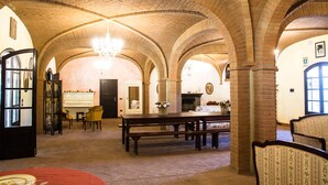 Un vaste hall doté de hauts plafonds en briques en forme d’arc, d’une cheminée centrale et d’un lustre.