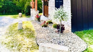 A house with a stone facade, a metal roof, and a wooden porch. - LUXURY COUPLES CABIN! Caveside Cabins (Creola)