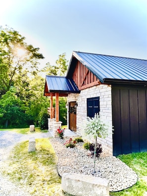 A house with a stone facade, a metal roof, and a wooden porch.