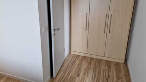 Een kamer met een houten garderobe, een witte deur en een houten vloer.