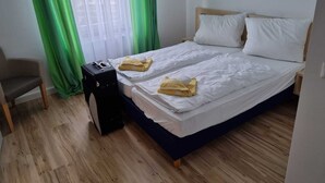 Een hotelkamer met twee bedden, een stoel, een koffer en een speaker.