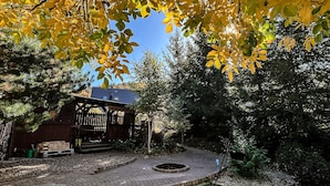 Ein Garten mit einem hölzernen Pavillon, einem Ziegelweg und einer runden Feuerstelle.