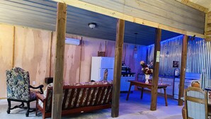 Un intérieur rustique avec des poutres apparentes, un coin repas avec une table et des chaises en bois, et une cuisine équipée d’un réfrigérateur et d’une cuisinière.
